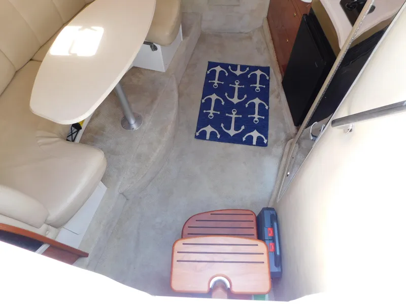 Slide: The Image of Interior of 2002 Rinker 310 Fiesta Vee boat with seating, table, and anchor-themed rug. - 34