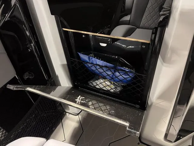 Slide: The Image of 2024 Yamaha Boats 255XE interior storage compartment with netting and sleek design. - 16