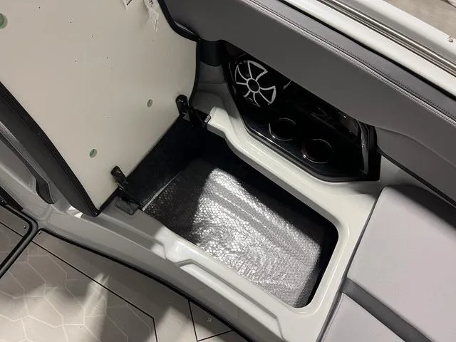 Slide: The Image of 2024 Yamaha Boats 255XE interior storage compartment with speaker and cup holders. - 26