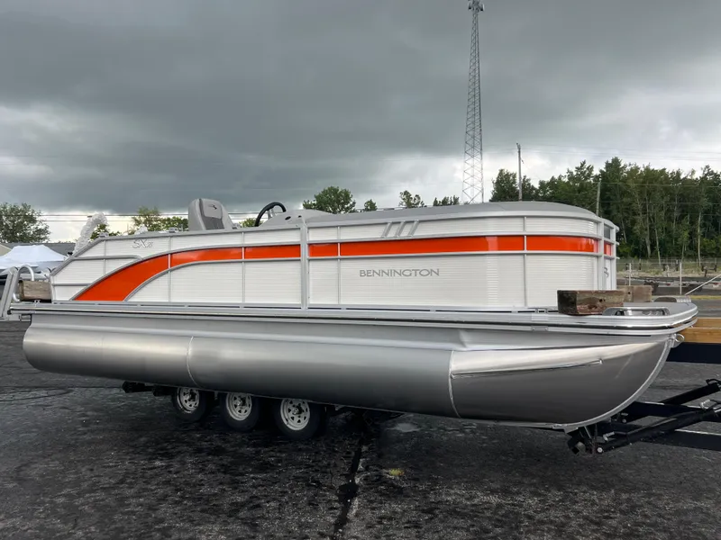 The Image of 2025 Bennington 21 SXSB pontoon boat with orange and white design on trailer. - 0