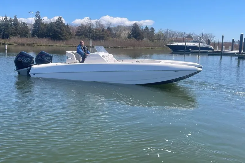 Slide: The Image of 2025 Hustler 25 C3 Speedfish boat on calm water with a person at the helm. - 12