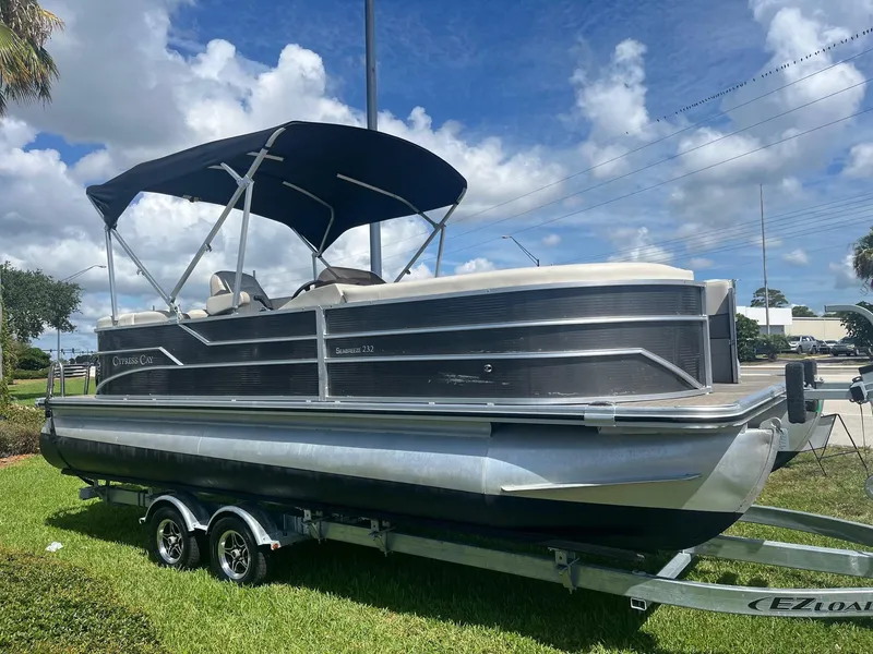 The Image of 2022 Cypress Cay Seabreeze 232 pontoon boat on trailer, blue canopy, parked on grass. - 0