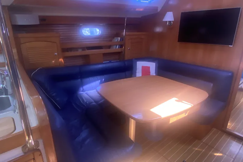 Slide: The Image of Luxurious 2007 Catalina 470 yacht interior with blue seating and wooden dining table. - 23