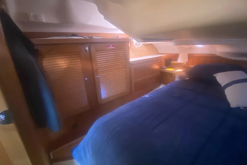Slide: The Image of Cozy cabin interior of 2007 Catalina 470 sailboat with wooden cabinetry and blue bedding. - 43