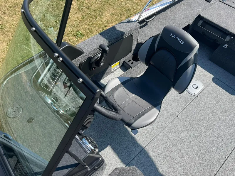 Slide: The Image of 2025 Lund 1875 Impact XS Sport boat interior with steering console and cushioned seat. - 17