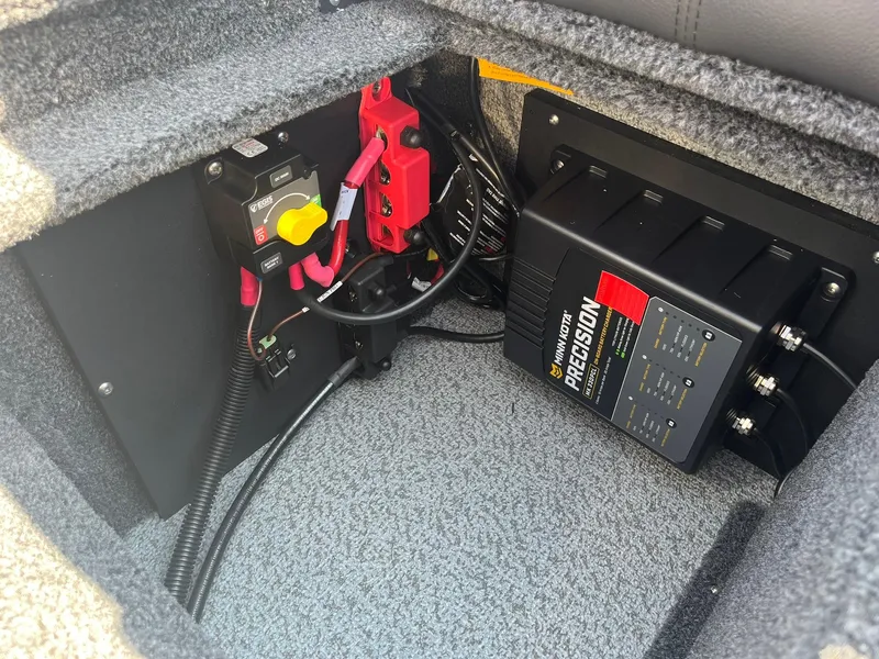 Slide: The Image of 2025 Lund 1875 Impact XS Sport boat battery compartment with precision charger and wiring. - 27