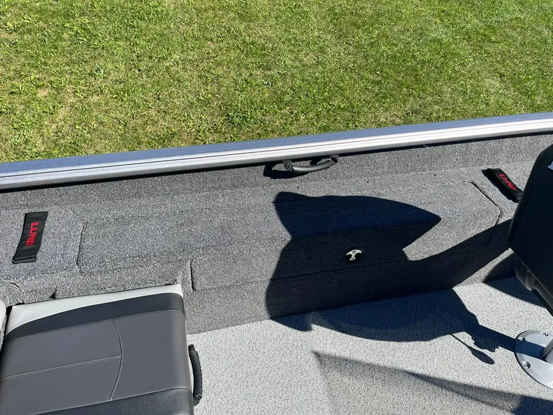 Slide: The Image of 2025 Lund 1775 Impact XS SS boat interior with seating and storage, on grass. - 20