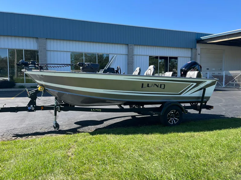 Slide: The Image of 2025 Lund 1775 Impact XS SS boat on trailer, parked outside a building. - 32