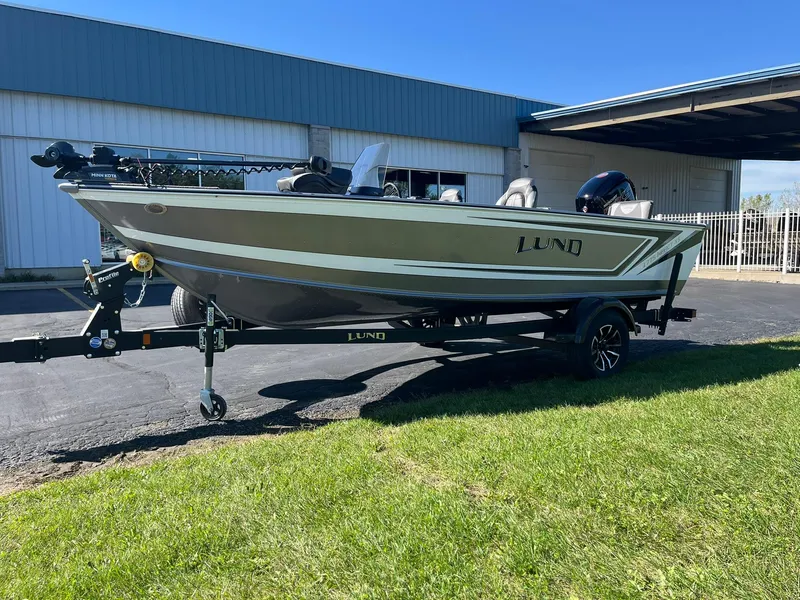 Slide: The Image of 2025 Lund 1775 Impact XS SS boat on trailer, parked outside a building. - 33