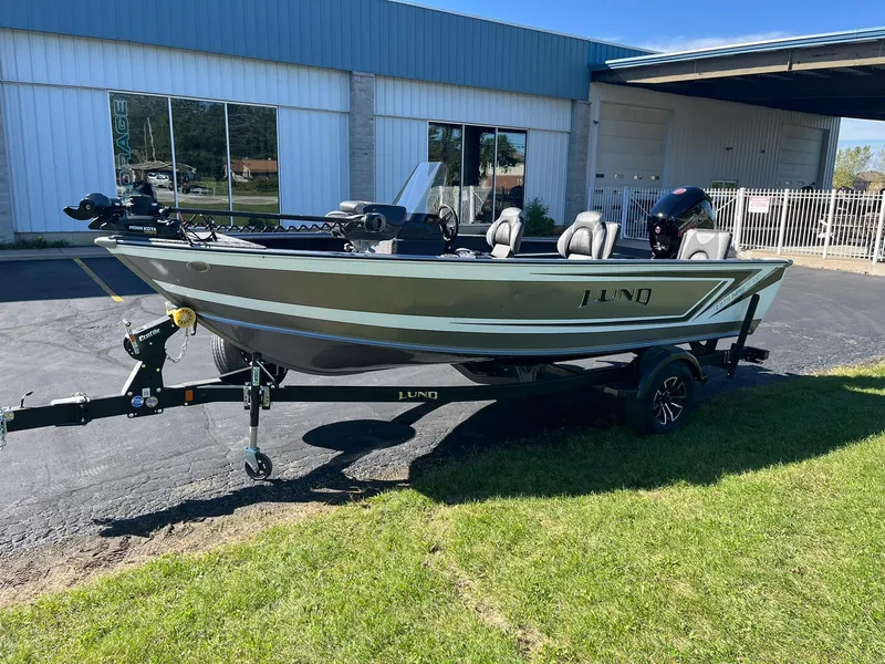 Slide: The Image of 2025 Lund 1775 Impact XS SS boat on trailer, parked outside a building. - 35
