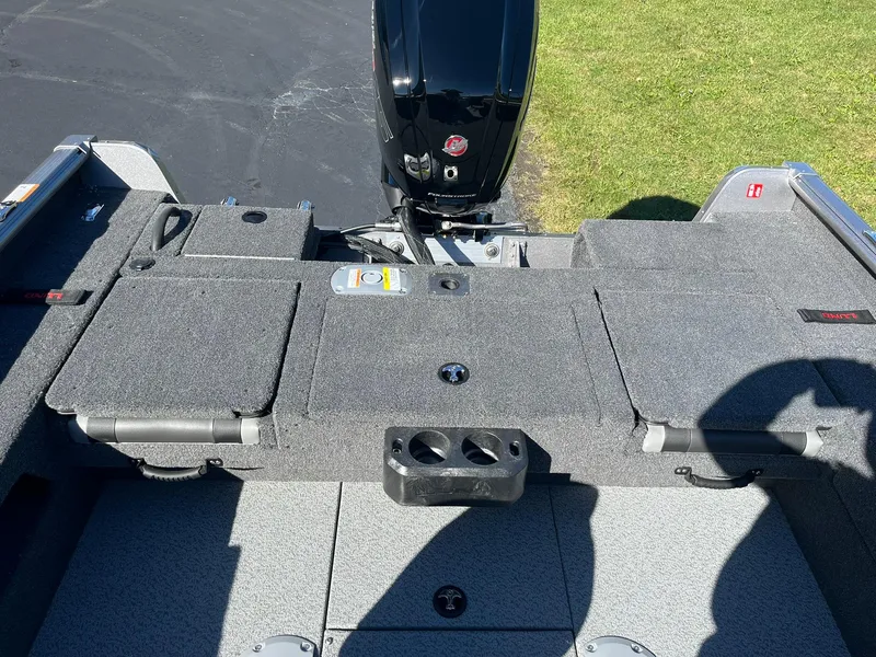 Slide: The Image of 2025 Lund 1775 Impact XS SS boat interior with motor, gray carpet, and storage compartments. - 6