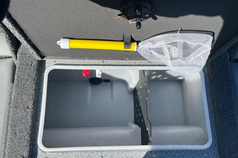 Slide: The Image of 2025 Lund 1775 Impact XS SS boat storage compartment with fishing net and yellow handle. - 8