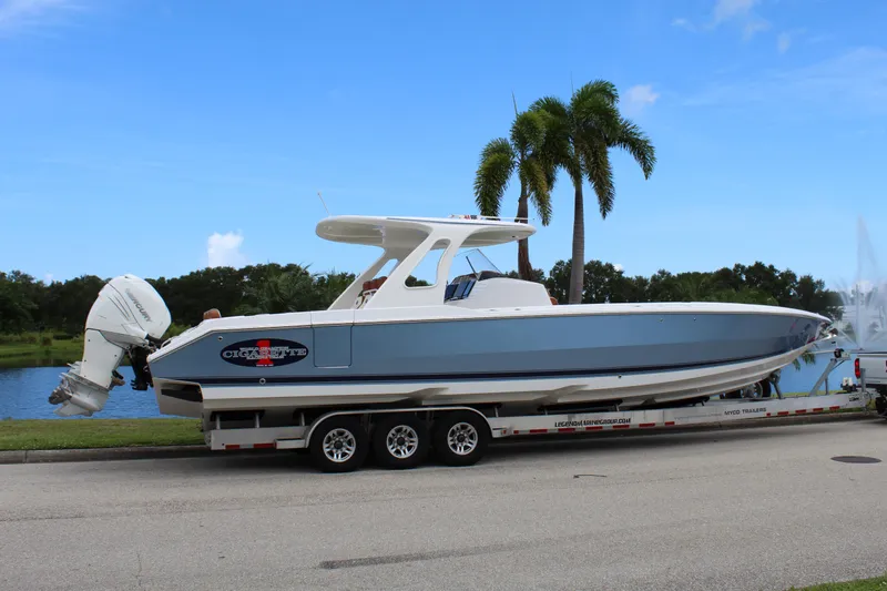 Slide: The Image of 2015 Cigarette 39 GTS boat on trailer by palm trees and water. - 10