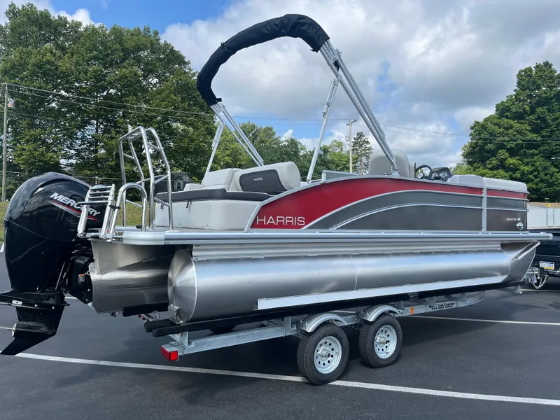 Slide: The Image of 2025 Harris Cruiser 210 pontoon boat on trailer, featuring a sleek design and Mercury outboard motor. - 2