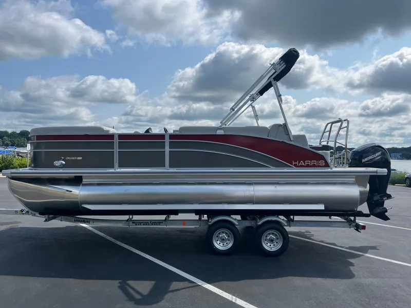 Slide: The Image of 2025 Harris Cruiser 210 pontoon boat on a trailer under a cloudy sky. - 4