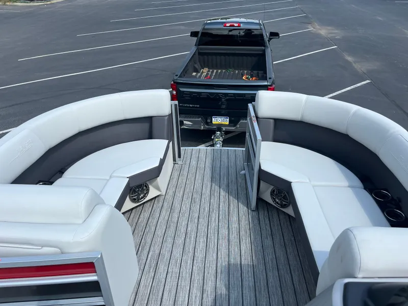 Slide: The Image of 2025 Harris Cruiser 210 pontoon boat interior with curved seating, parked near a black pickup truck. - 9