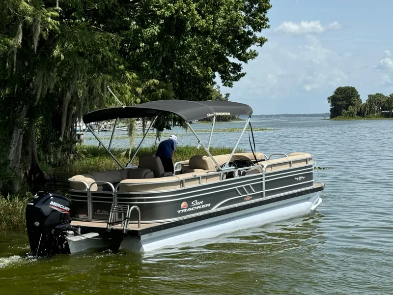 Slide: The Image of 2023 Sun Tracker Party Barge 24 DLX pontoon boat on a serene lake. - 2