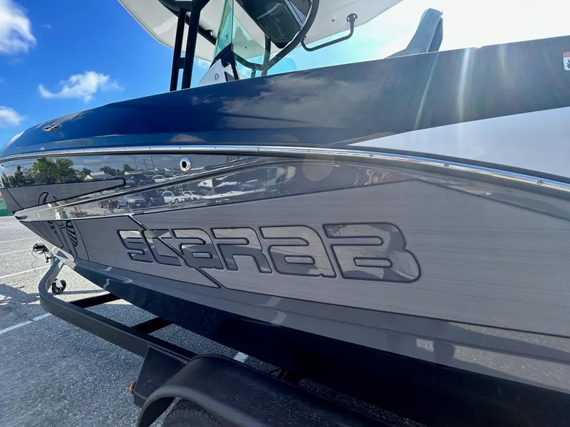 Slide: The Image of 2024 Scarab 255 Open ID boat side view in a parking lot. - 5