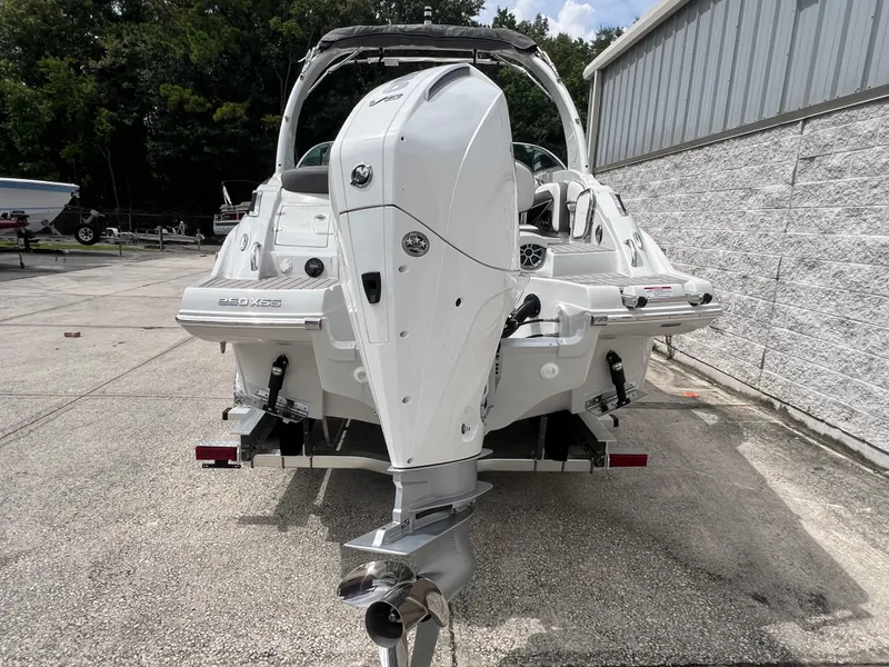 Slide: The Image of 2024 Crownline 250 XSS boat, rear view with outboard motor, parked on a trailer. - 10
