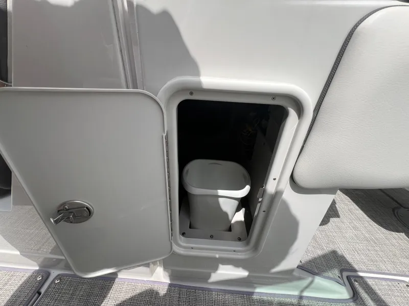 Slide: The Image of 2024 Crownline 250 XSS boat interior storage compartment with a portable toilet. - 11