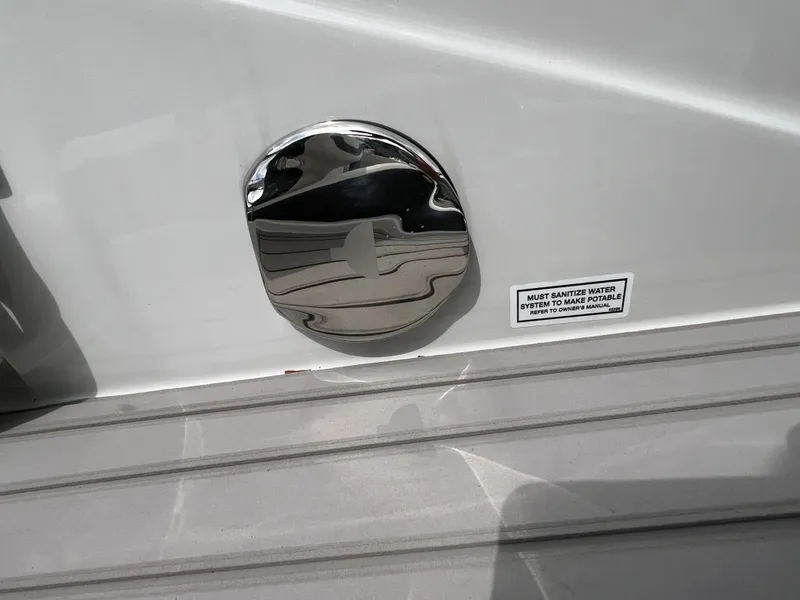 Slide: The Image of 2024 Crownline 250 XSS boat detail with chrome fixture and safety label. - 24