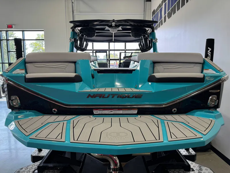 Slide: The Image of 2025 Nautique Super Air Nautique G25 boat, rear view in showroom, teal color. - 8