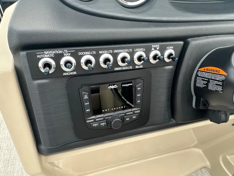 Slide: The Image of Control panel of 2024 Berkshire 22RFX ARCH CTS 2.75 boat with various switches and a sound system. - 16