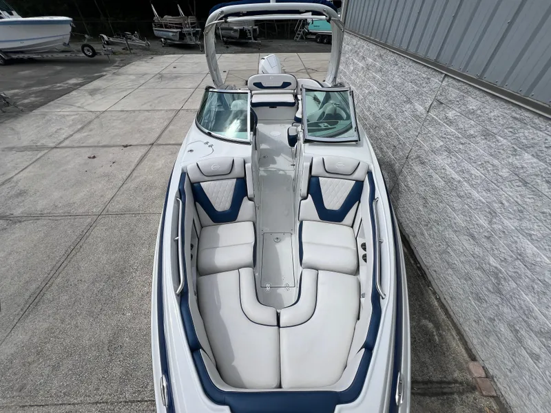 Slide: The Image of 2024 Crownline 270 XSS boat with white and blue interior, docked near a warehouse. - 2