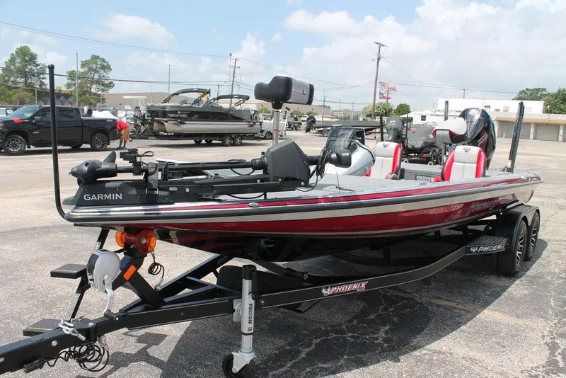 Slide: The Image of 2025 Phoenix 921 ELITE bass boat with Garmin electronics on a trailer in a parking lot. - 2