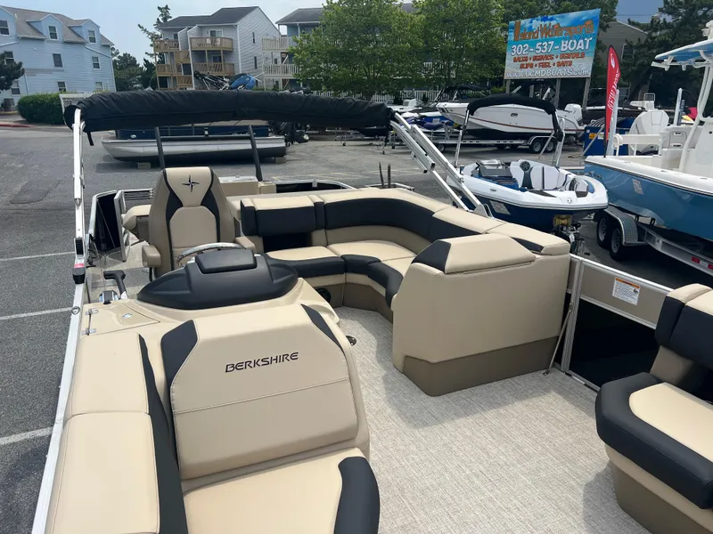 Slide: The Image of 2024 Berkshire 23RFC STS 2.75 pontoon boat with beige and black seating in a marina. - 4