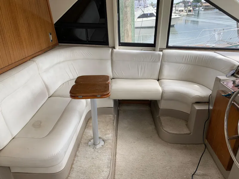 Slide: The Image of 1999 Bayliner 5788 Pilot House Motoryacht interior with white leather seating and wooden table. - 21
