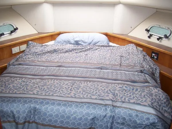 Slide: The Image of Cozy bedroom in 1999 Bayliner 5788 Pilot House Motoryacht with patterned bedding and porthole windows. - 26