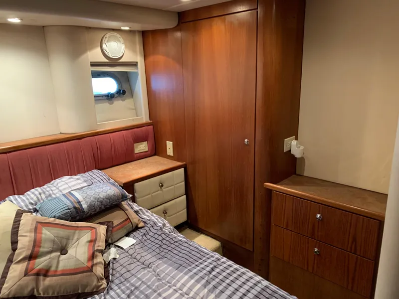 Slide: The Image of 1999 Bayliner 5788 Pilot House Motoryacht bedroom with wood cabinetry and cozy bedding. - 27