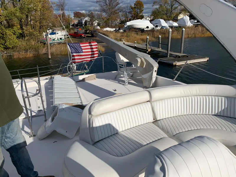 Slide: The Image of 1999 Bayliner 5788 Pilot House Motoryacht with American flag, docked near trees and water. - 34