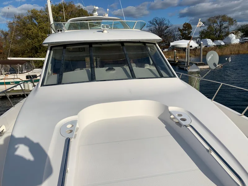 Slide: The Image of 1999 Bayliner 5788 Pilot House Motoryacht on water, showcasing sleek design and spacious deck. - 4