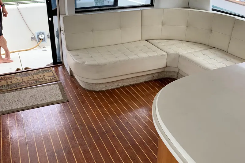 Slide: The Image of 1999 Bayliner 5788 Pilot House Motoryacht interior with white seating and wooden flooring. - 7