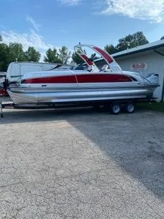 The Image of 2024 Manitou XT RFXW SHP pontoon boat on trailer, parked outdoors. - 0