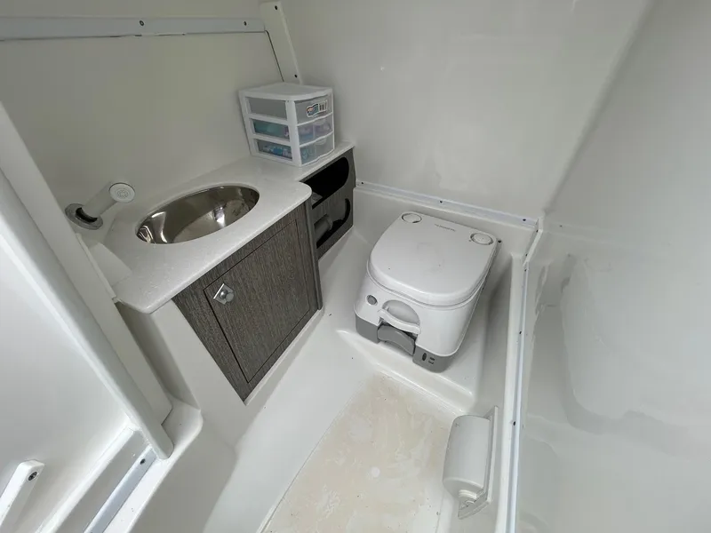 Slide: The Image of 2021 Monterey M65 boat bathroom with sink, storage cabinet, and portable toilet. - 22
