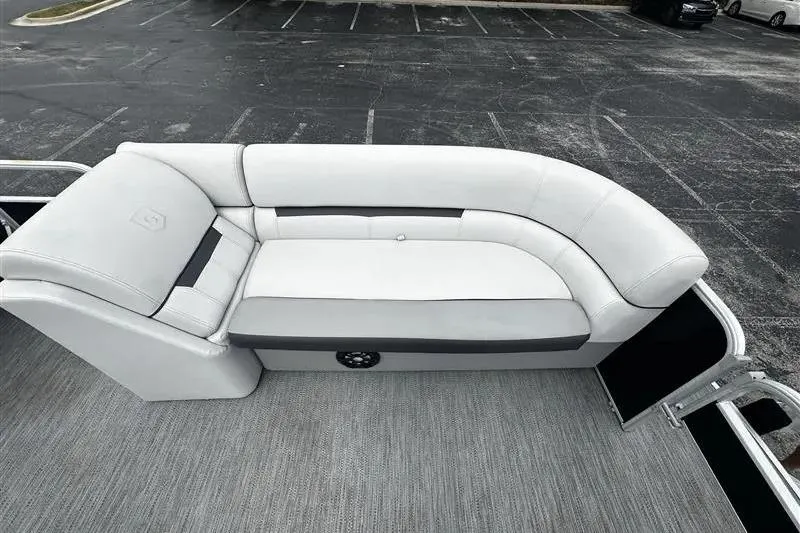 Slide: The Image of 2023 Godfrey 2286 boat interior with white cushioned seating in a parking lot. - 15
