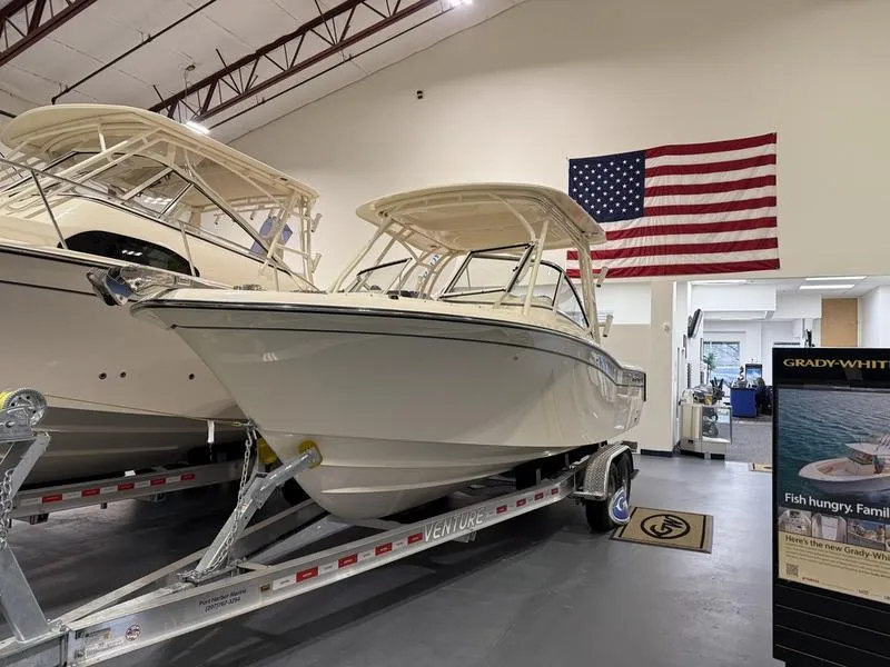 Slide: The Image of 2025 Grady-White Freedom 235 boat in showroom with American flag backdrop. - 3