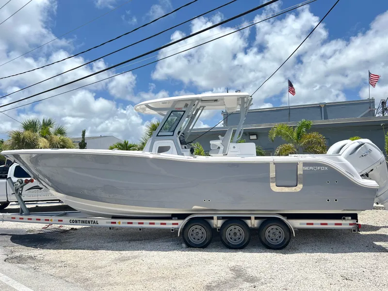 The Image of 2025 Sea Fox 328 Commander boat on a Continental trailer, parked outdoors. - 0