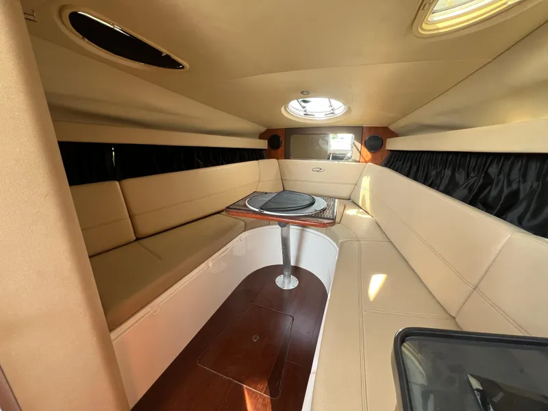 Slide: The Image of Interior of 2012 Regal 28 Express boat with beige seating and wooden table. - 12