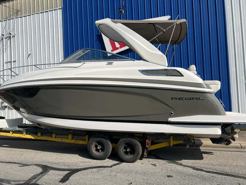 Slide: The Image of 2012 Regal 28 Express boat on trailer, parked by blue and white building. - 28