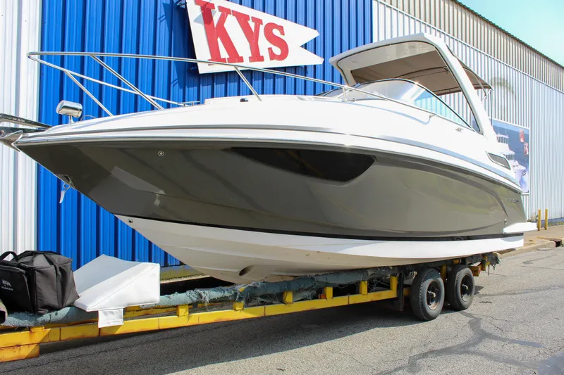 Slide: The Image of 2012 Regal 28 Express boat on trailer, parked near blue building. - 3