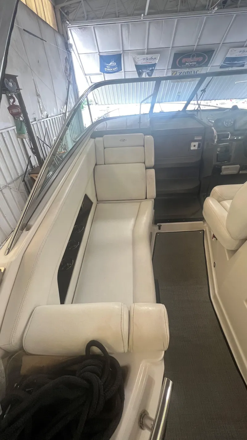 Slide: The Image of 2012 Regal 28 Express boat interior with white seating and dashboard in a garage. - 33
