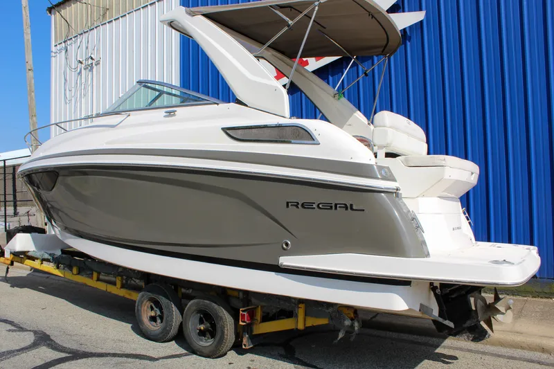 Slide: The Image of 2012 Regal 28 Express boat on trailer, parked near blue building. - 5