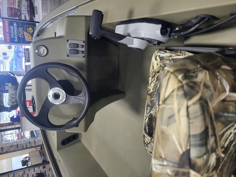 Slide: The Image of 2024 Tracker Grizzly 1754 SC boat interior with steering wheel and camo seat. - 6