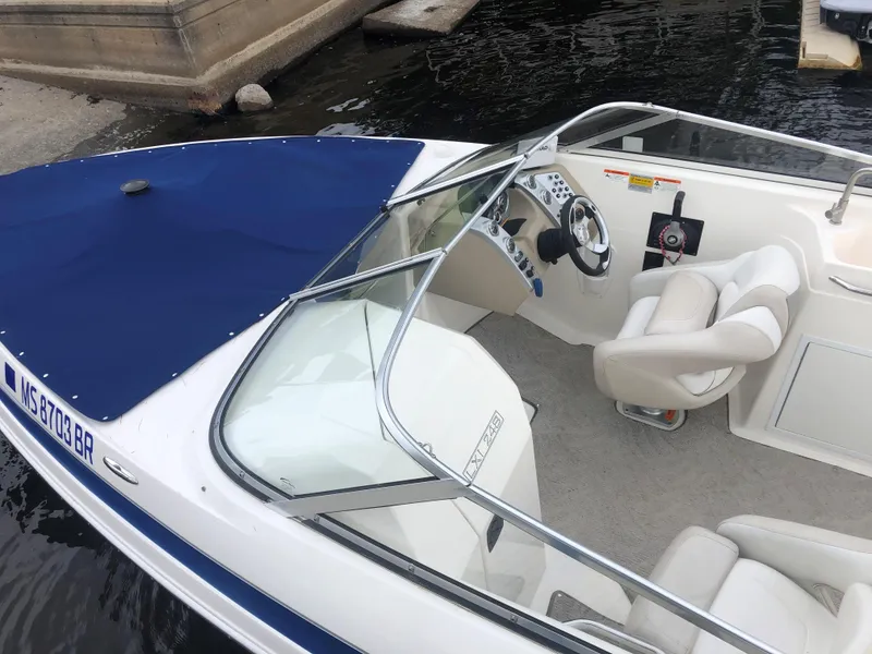 Slide: The Image of 2006 Larson 248 LXI boat with blue cover and white interior, docked by the water. - 11