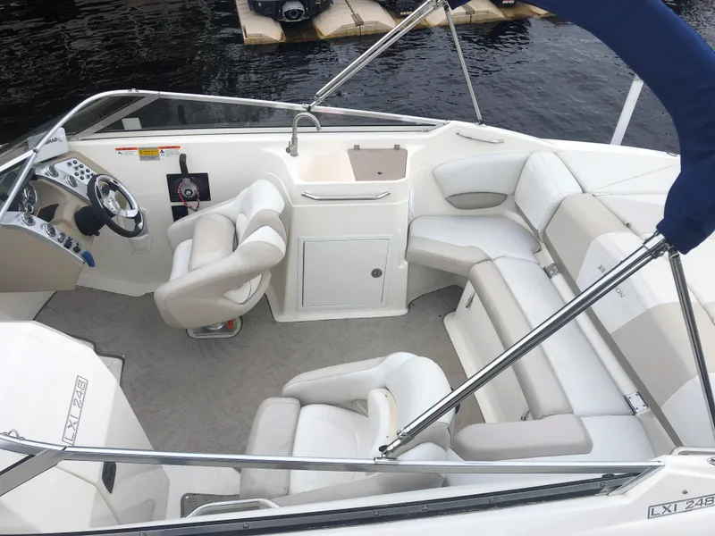 Slide: The Image of 2006 Larson 248 LXI boat interior with seating and steering wheel, docked by the water. - 13
