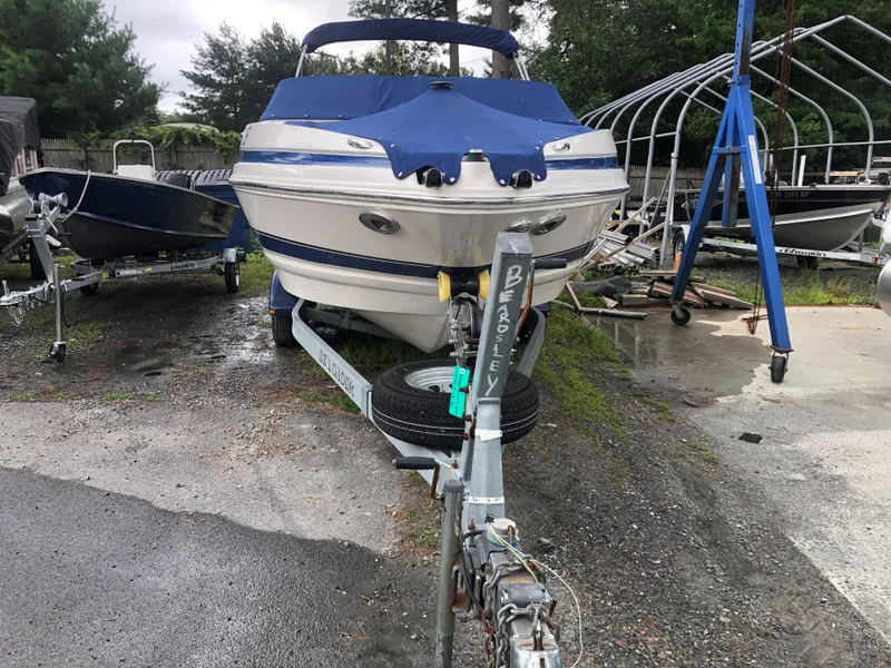 Slide: The Image of 2006 Larson 248 LXI boat on trailer, covered, parked outdoors. - 3